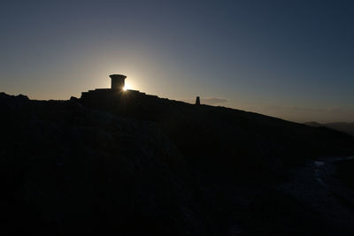 Scenic view of silhouette mountains against clear sky during sunset