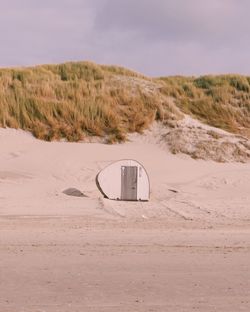 Lifeguard hut at beach against cloudy sky