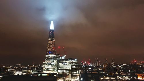 Illuminated buildings in city against sky at night