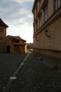 Street amidst buildings against sky during sunset