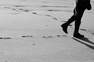 Low section of man walking on sand at beach