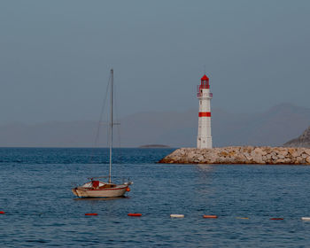 Lighthouse by sea against clear sky