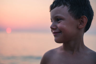 Shirtless boy at sea against sky