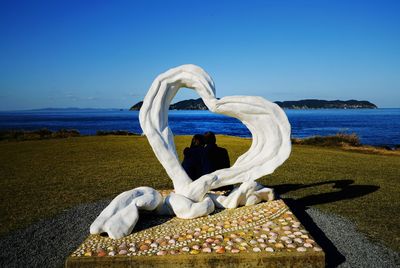 Love on beach against clear blue sky