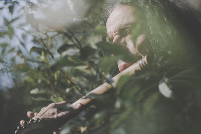 Man playing flute while standing in forest