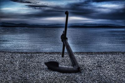 Deck chairs on beach against sky at dusk