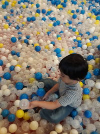 Full length of cute boy sitting in colorful balloons