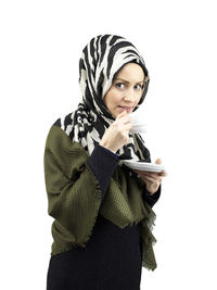 Portrait of young woman standing against white background