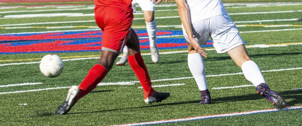 Low section of people playing soccer on field