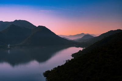 Scenic view of lake and mountains against sky during sunrise