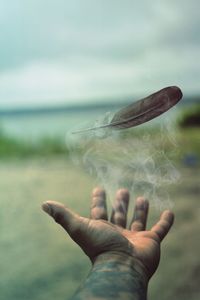 Feather levitating over man hand outdoors