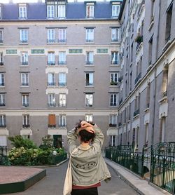 Rear view of woman standing against buildings in city