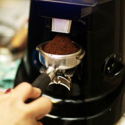 Ground coffee filling up an espresso basket by a barista.
