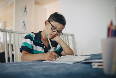 Close-up of disabled boy writing on book while sitting at table