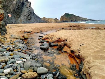 Surface level of rocks on beach against sky