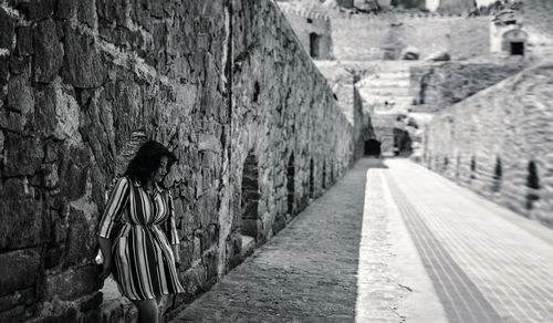 Woman walking in alley amidst buildings