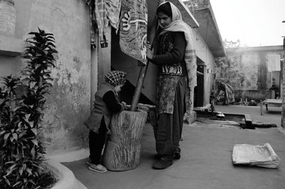 Mother with daughter mixing in container while standing outdoors