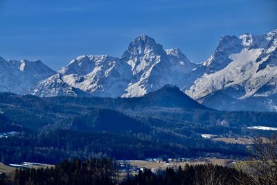 Scenic view of landscape with forests and snowcapped mountains against sky