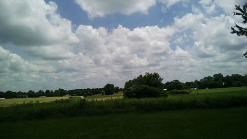 Scenic view of grassy field against cloudy sky