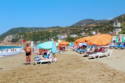 People at beach against clear blue sky