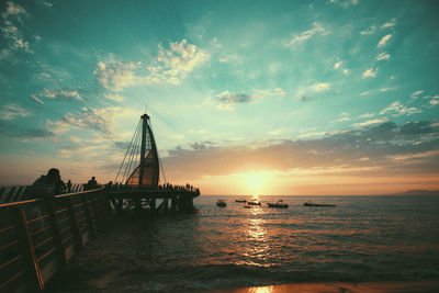 Bridge over sea against sky during sunset