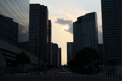 Street amidst buildings against sky during sunset