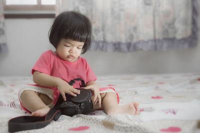 Cute girl sitting on bed at home