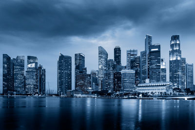 Sea by modern buildings against sky in city