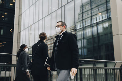 Business people walking on bridge in city during pandemic