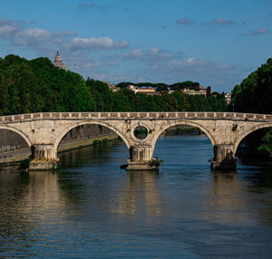 Arch bridge over river against sky