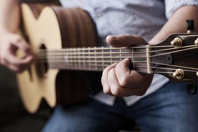 Midsection of man playing guitar