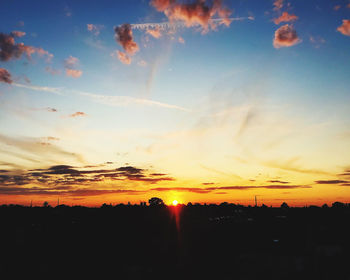 Scenic view of silhouette landscape against dramatic sky during sunset