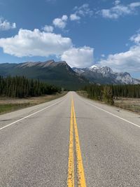 Road leading towards mountains against sky