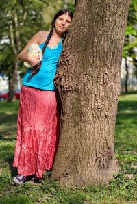Young hipster woman leaning against the tree in the park