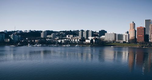 Scenic view of river by buildings against clear sky