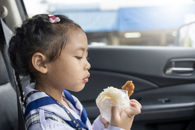 Close-up of girl eating food in car