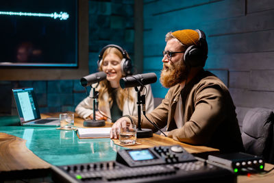 Two young stylish radio show hosts record fresh podcast episode in home loft studio apartment