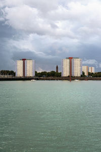 Sea by buildings against sky in city