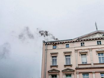 Low angle view of smoke emitting from building against sky