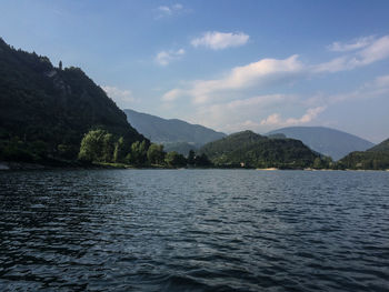 Scenic view of river by mountains against sky