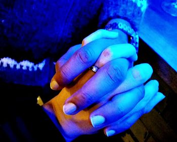 Close-up of woman hand on blue wall