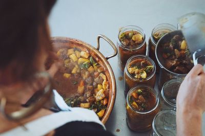 Woman putting cooked food in jars