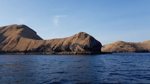 Scenic view of sea and mountains against blue sky