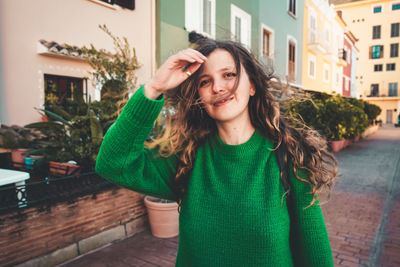 Portrait of smiling woman standing against building