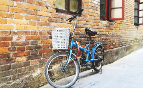 Bicycle parked against brick wall