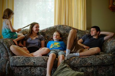 Full length of happy friends sitting on sofa at home