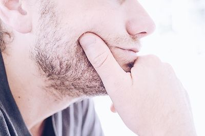 Cropped image of man with hand on chin against white background