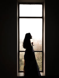 Rear view of woman looking through window