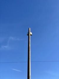 Low angle view of bird on wooden post against sky