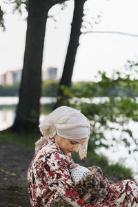 Mother breastfeeding baby at lake